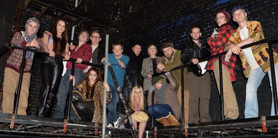 colour photo. all of the actors from rent, each dressed in unique styles, look into the camera